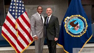 Delray Beach Police Assistant Chief Anthony Martinez Standing Beside An Fbi National Academy Flag After Graduating From Session 298.
