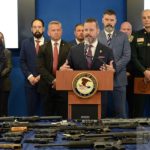 U.s. Attorney Jason A. Reding Quiñones Speaks At A Podium With Federal And Local Law Enforcement Officials Behind Him.